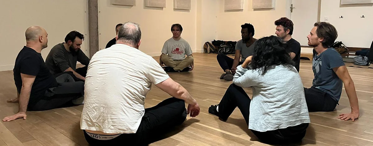 Les pratiquants assis en cercle sur le parquet du dojo, pendant un temps d'échange au cours d'une séance.