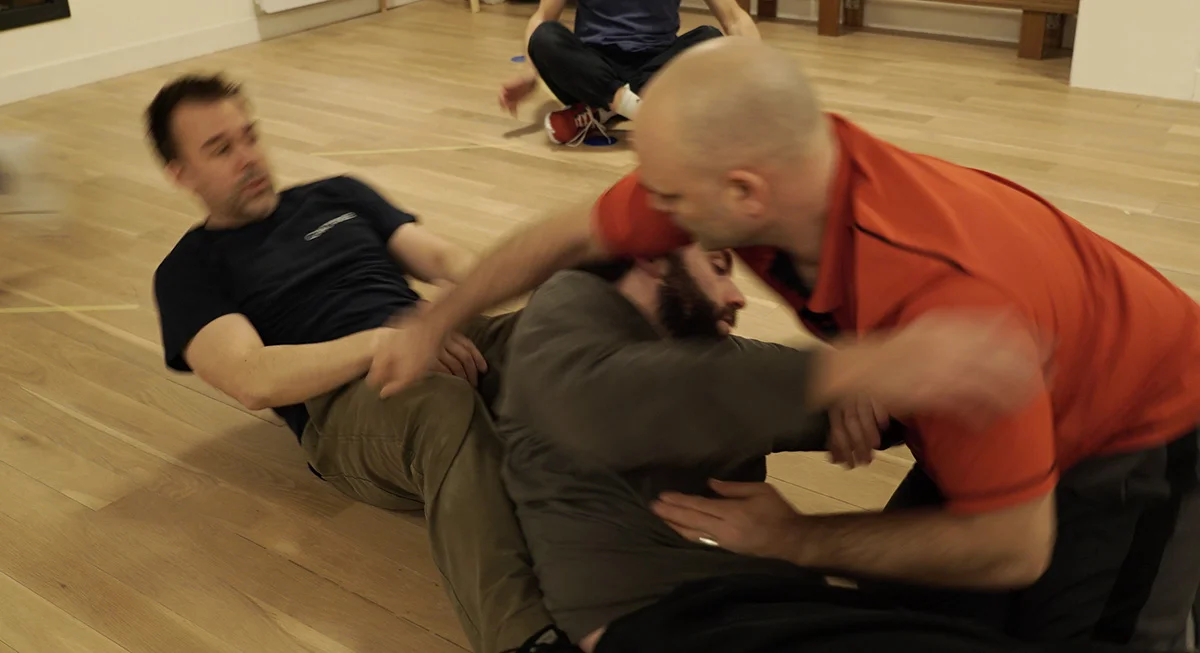 Trois pratiquants engagés dans un exercice de travail au sol.