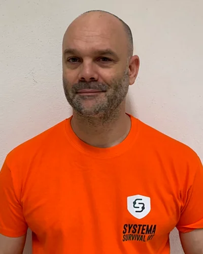 Xavier, crâne rasé et barbe courte, en tee-shirt orange.